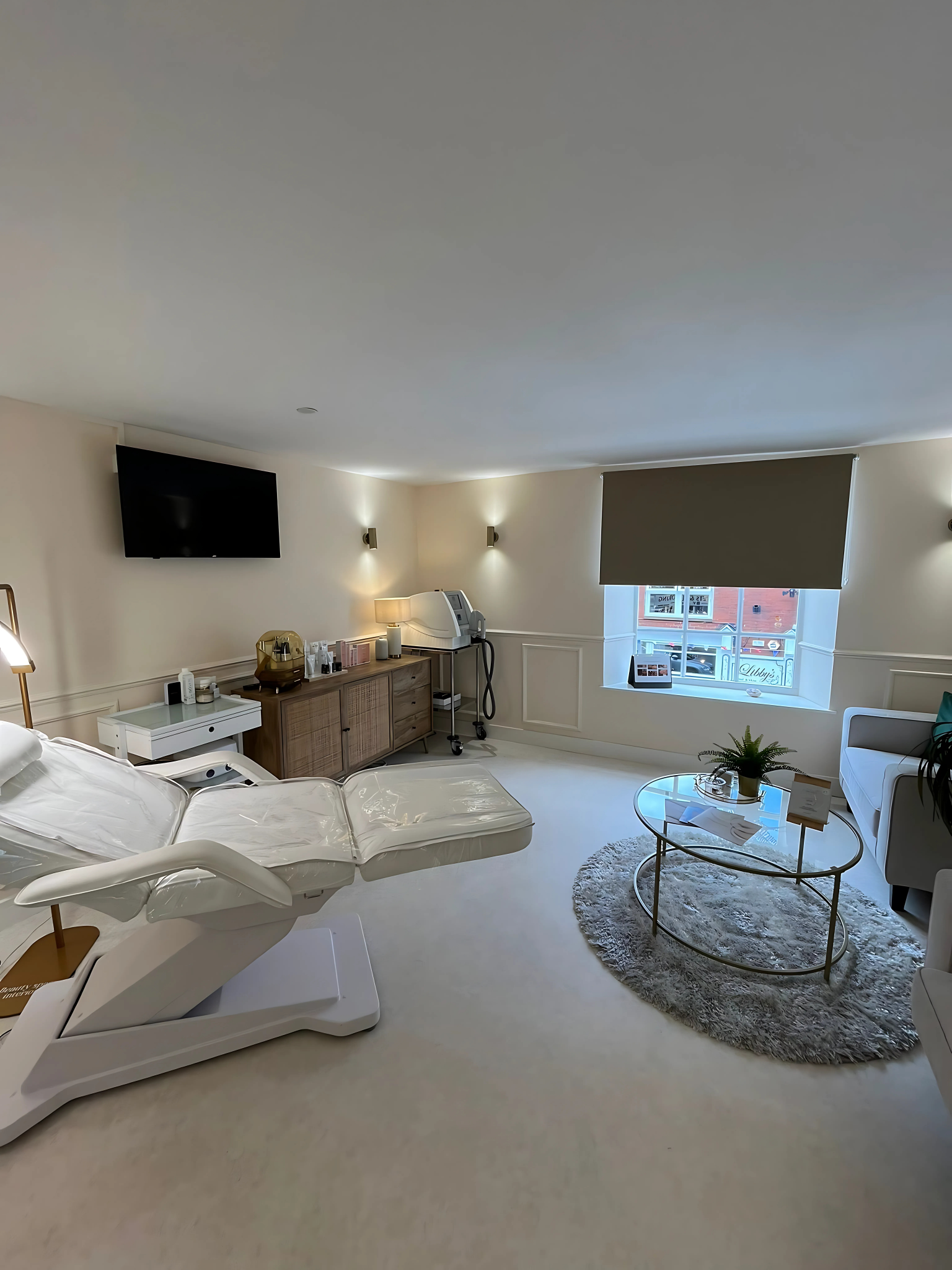 Modern living room with white furniture, TV, and a desk.