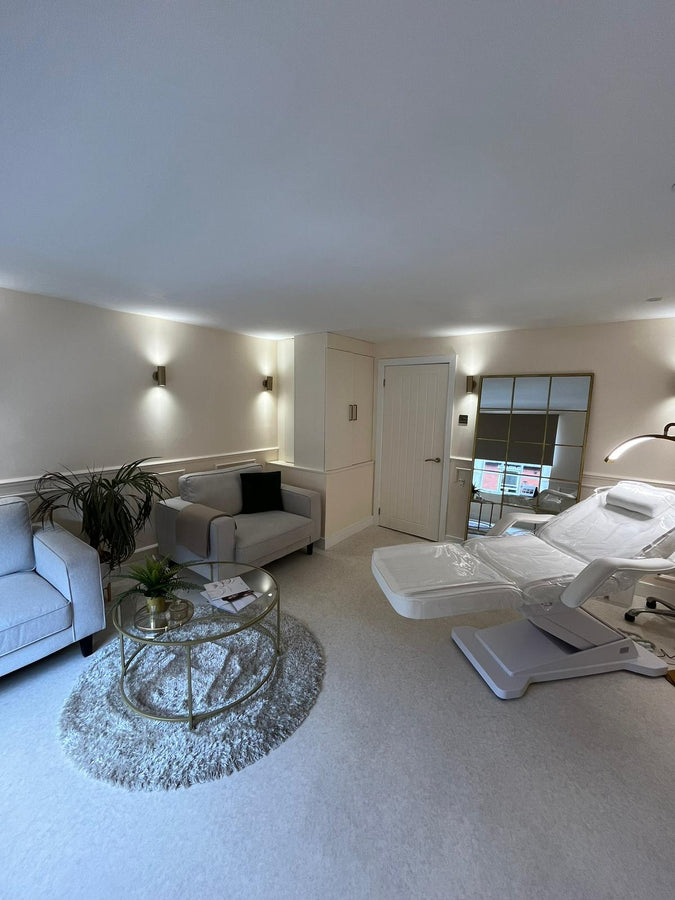 Modern aesthetics room with gray sofa, glass coffee table, and white clinic chair