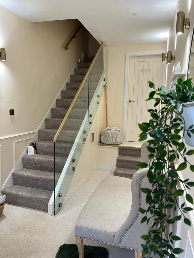 Staircase with carpeted steps leading to a landing with a chair and plant.